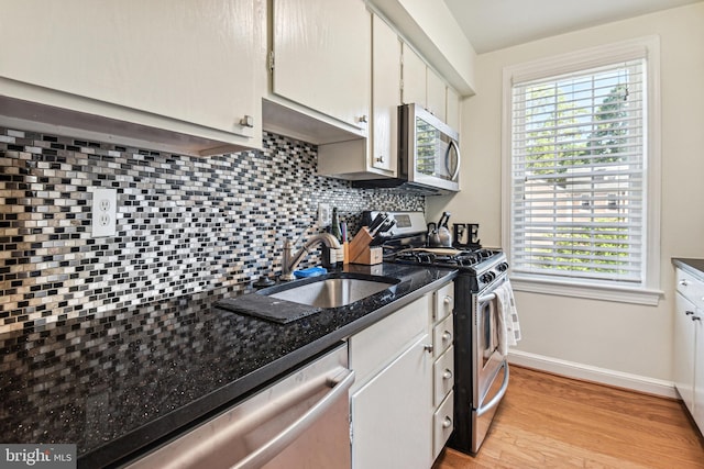 kitchen with light wood finished floors, baseboards, a sink, stainless steel appliances, and backsplash