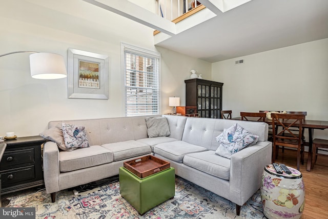 living room featuring a skylight, visible vents, and wood finished floors