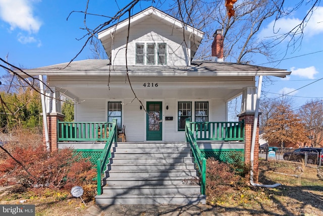 bungalow with stairs, a porch, and a chimney