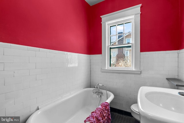 full bath with a freestanding tub, toilet, a sink, tile walls, and tile patterned floors