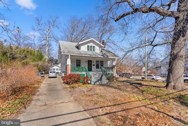 bungalow-style home featuring driveway, a porch, and a chimney