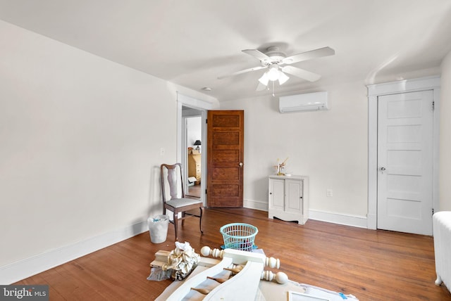 living area featuring baseboards, wood finished floors, and a wall mounted air conditioner