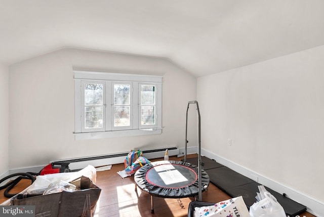 workout area featuring vaulted ceiling, a baseboard heating unit, wood finished floors, and baseboards