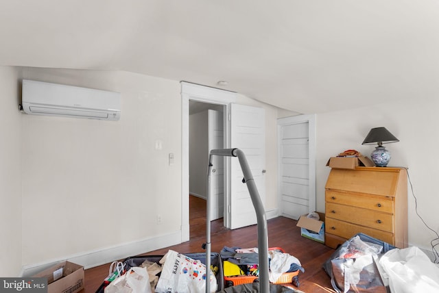 bedroom with vaulted ceiling, dark wood-type flooring, and an AC wall unit