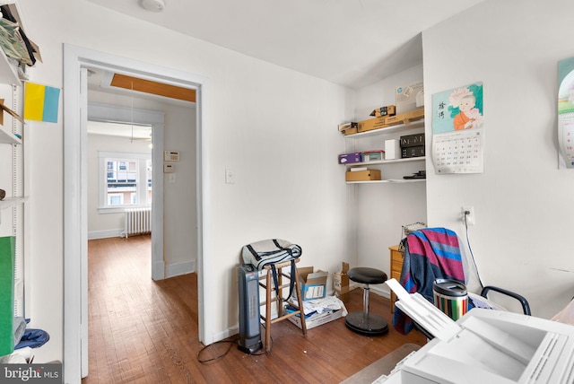 interior space with radiator, attic access, baseboards, and wood finished floors