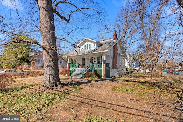 bungalow with covered porch, a chimney, and brick siding