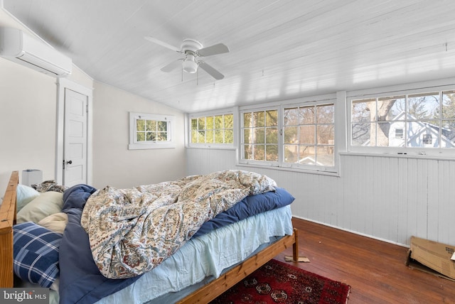 bedroom featuring a wall unit AC, vaulted ceiling, dark wood finished floors, and a ceiling fan