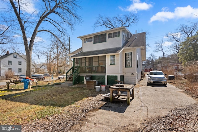 view of front of house featuring stairs, driveway, and a sunroom