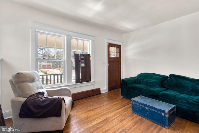 living room with baseboards, baseboard heating, and wood finished floors