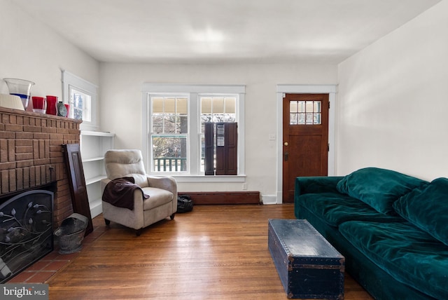 living area featuring dark wood-type flooring, a wealth of natural light, a fireplace, and baseboards