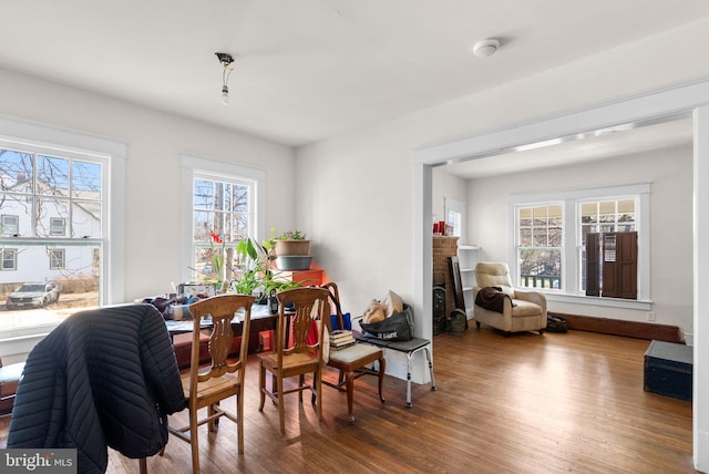 dining space with a brick fireplace and wood finished floors