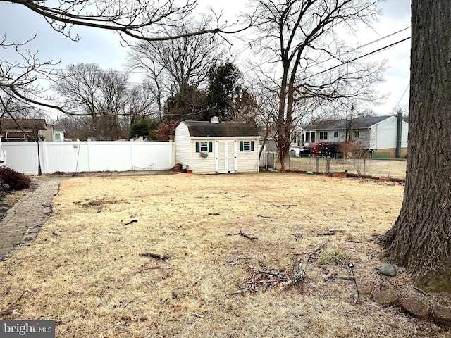 view of yard with a fenced backyard, a storage unit, and an outdoor structure