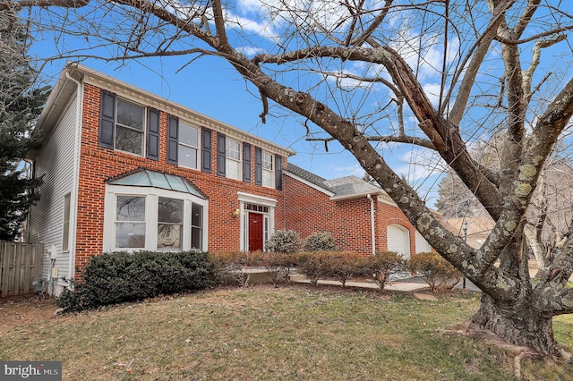 colonial-style house featuring a garage, brick siding, fence, and a front lawn