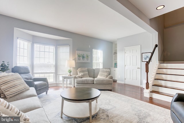 living area with plenty of natural light, stairway, baseboards, and wood finished floors