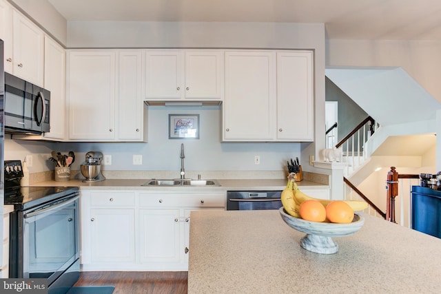 kitchen with stainless steel electric range oven, white cabinetry, light countertops, and a sink