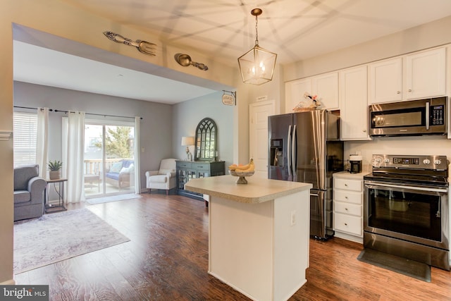 kitchen featuring light countertops, hanging light fixtures, appliances with stainless steel finishes, open floor plan, and white cabinets