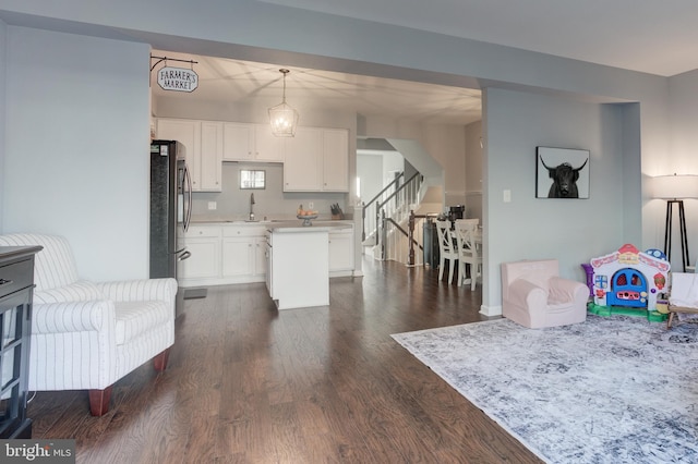 kitchen featuring dark wood-type flooring, decorative light fixtures, freestanding refrigerator, light countertops, and white cabinetry