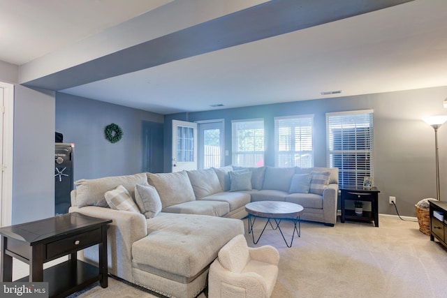 living room with baseboards, visible vents, and light colored carpet