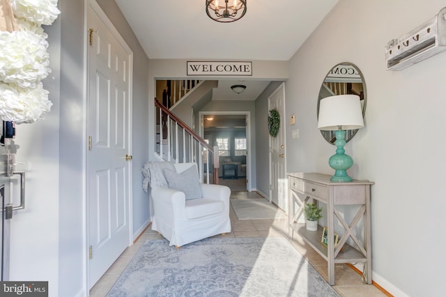 foyer entrance with baseboards, stairway, an inviting chandelier, and light tile patterned floors