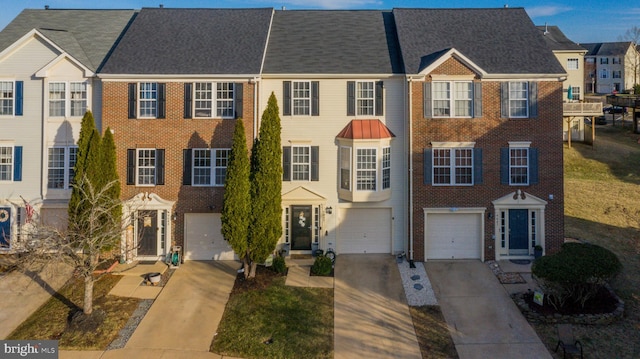 townhome / multi-family property featuring driveway, a garage, and brick siding