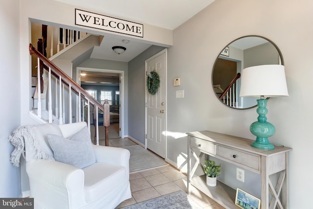 foyer entrance with stairway, baseboards, and light tile patterned floors