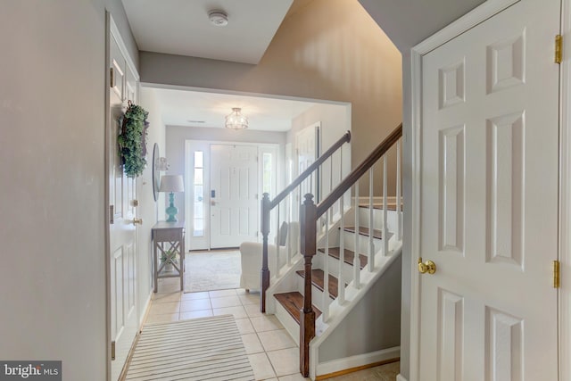 foyer entrance with stairs and light tile patterned flooring