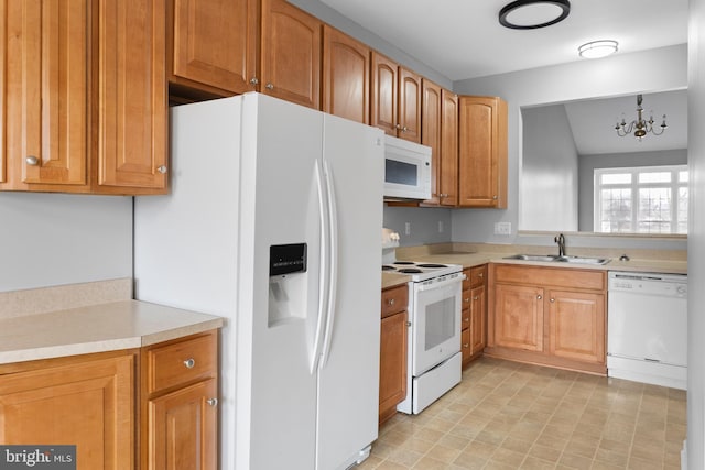 kitchen with white appliances, brown cabinetry, light countertops, a chandelier, and a sink