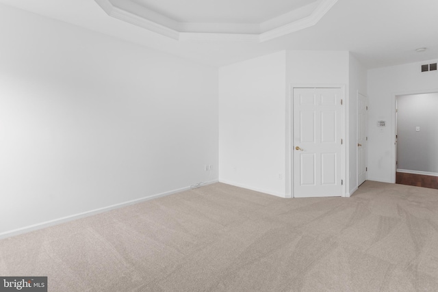 carpeted empty room with a raised ceiling, visible vents, and baseboards