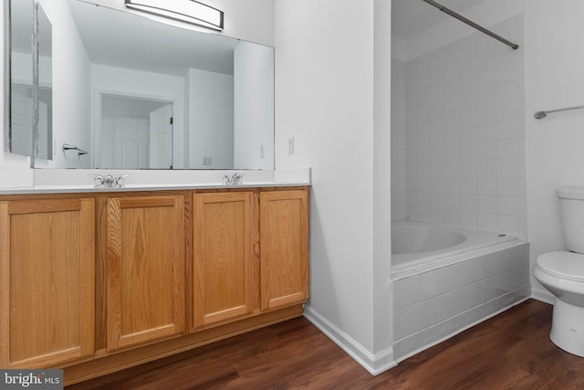 full bath with a sink, double vanity, wood finished floors, and toilet