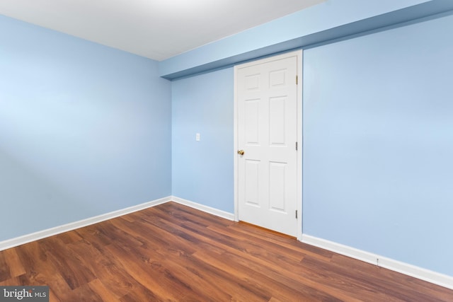 empty room featuring dark wood finished floors and baseboards