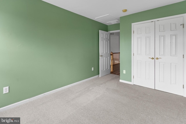 unfurnished bedroom featuring attic access, carpet, a closet, and baseboards