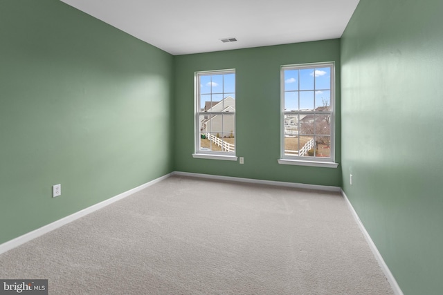 empty room with carpet flooring, visible vents, and baseboards