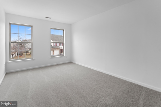 empty room featuring carpet floors, baseboards, and visible vents