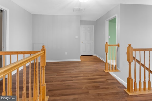 corridor featuring visible vents, wood finished floors, an upstairs landing, and baseboards