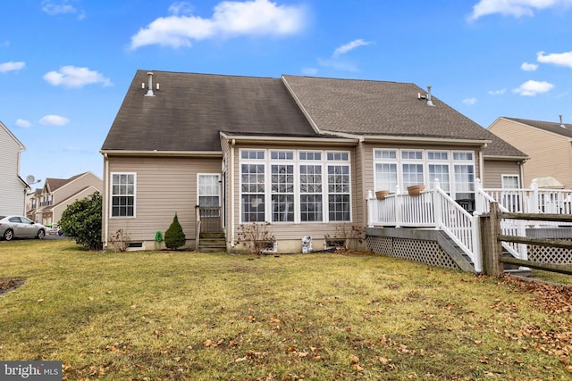 back of property featuring a shingled roof, a lawn, and a wooden deck