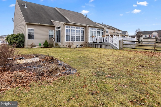 back of property with a deck, a yard, fence, and entry steps