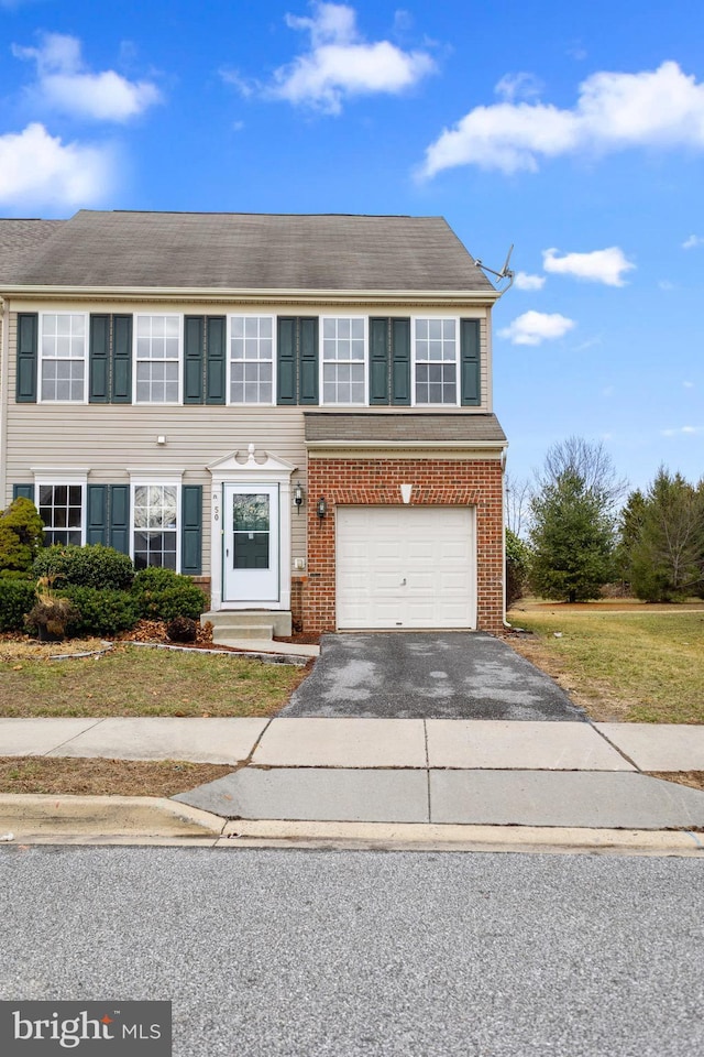 view of front of property featuring driveway, an attached garage, and brick siding