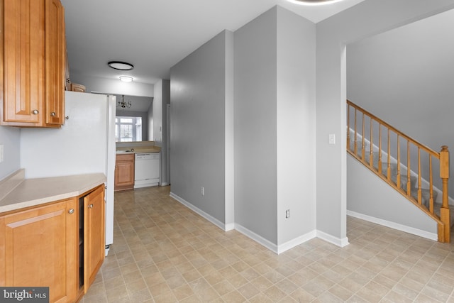 kitchen featuring light countertops, white dishwasher, and baseboards