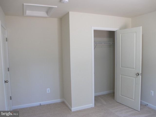 unfurnished bedroom featuring baseboards, a closet, and light colored carpet