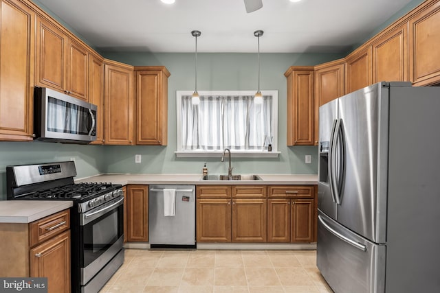 kitchen with stainless steel appliances, brown cabinetry, a sink, and light countertops