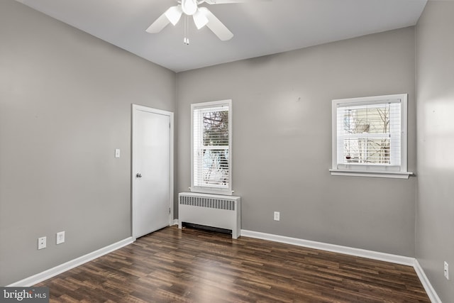 empty room featuring baseboards, ceiling fan, radiator heating unit, and wood finished floors