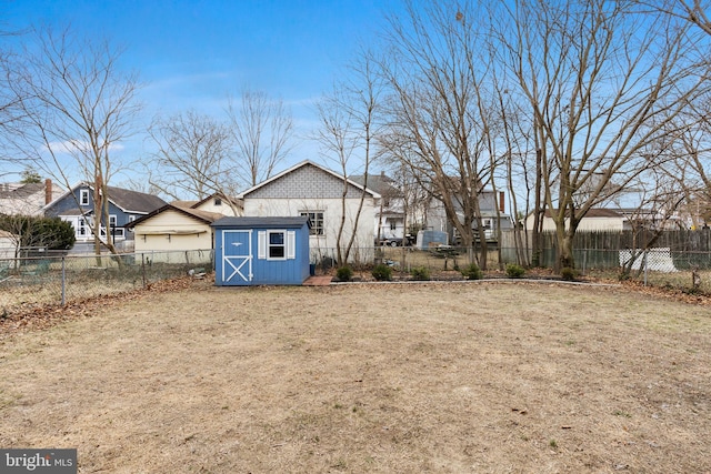 exterior space featuring a storage shed, a fenced backyard, and an outbuilding