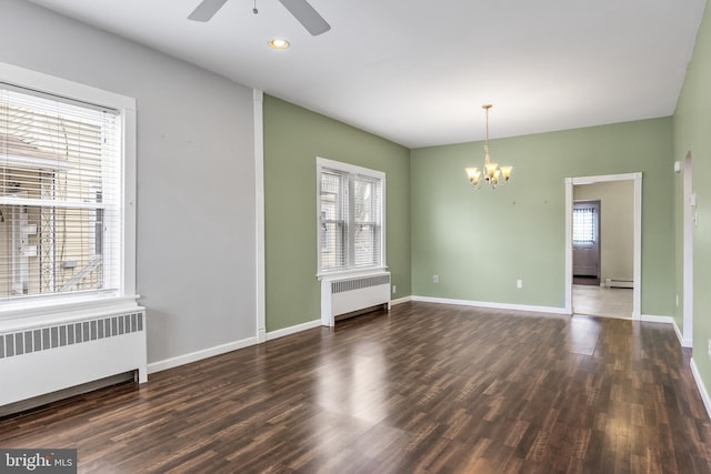 empty room featuring a baseboard heating unit, radiator, baseboards, and wood finished floors