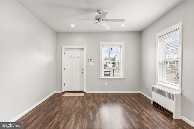 foyer featuring radiator heating unit, baseboards, a wealth of natural light, and wood finished floors