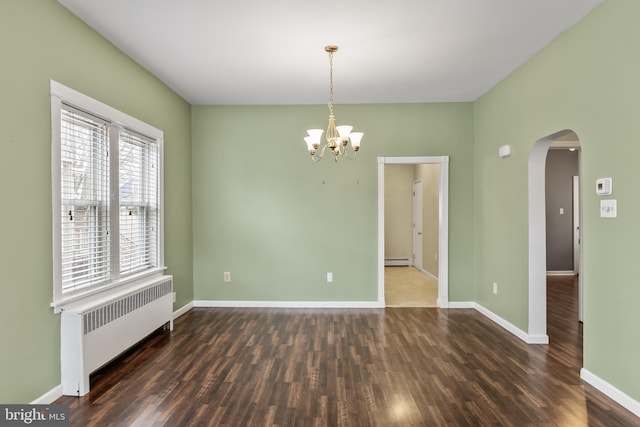 empty room with arched walkways, a baseboard radiator, radiator, wood finished floors, and baseboards