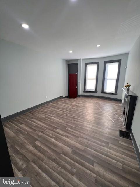 unfurnished living room with baseboards, dark wood-style flooring, and recessed lighting