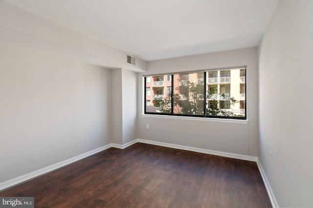 empty room featuring visible vents, baseboards, and wood finished floors