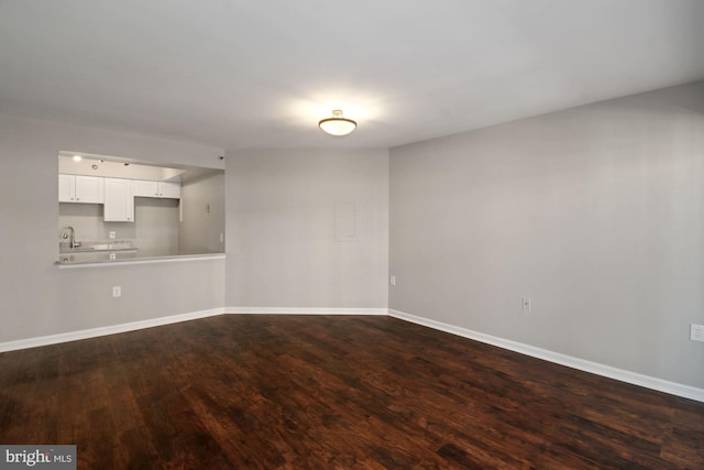 unfurnished living room with dark wood-style floors, baseboards, and a sink