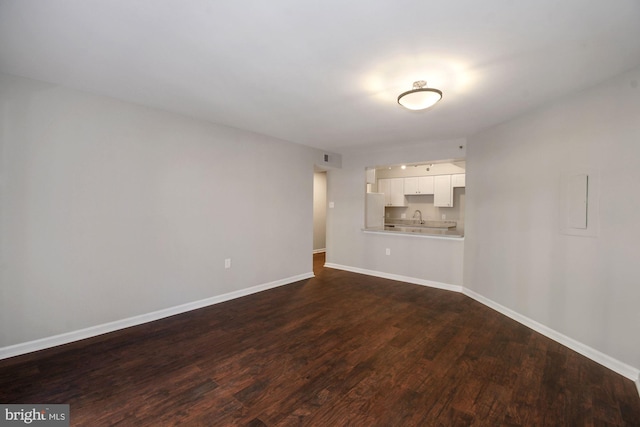 unfurnished living room with a sink, baseboards, and dark wood-style floors