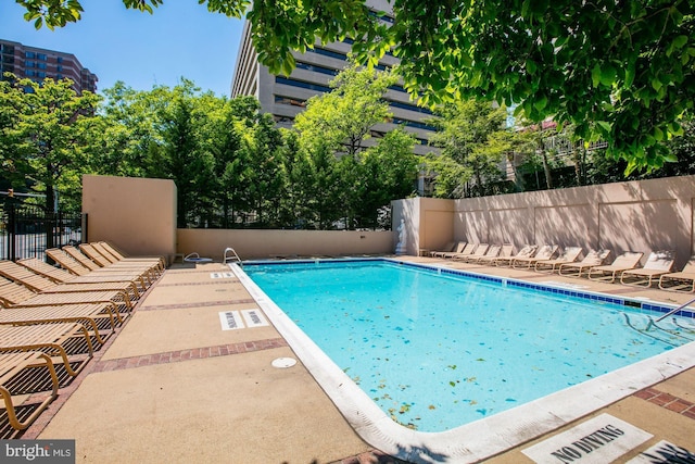 community pool with a patio area and fence